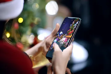 A player using their smartphone during a festive local event, representing KG999’s fully mobile-friendly casino.