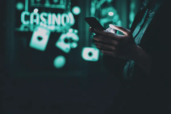 A person using their device against a moody casino-themed background, illustrating the smooth re-entry process at KG999.